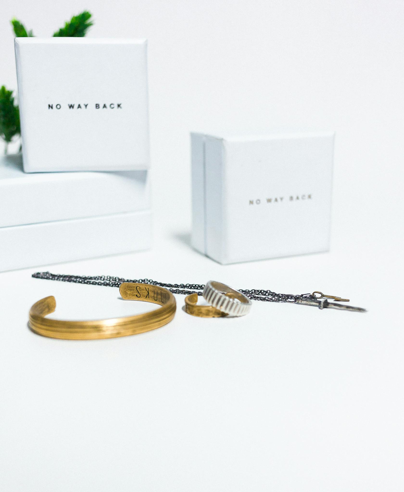 Close-up of gold and silver jewelry with white 'No Way Back' boxes on a white background.